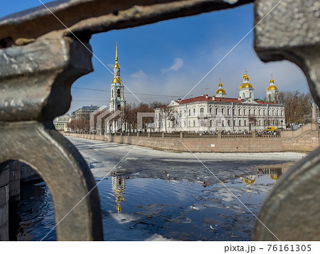 St. Nicholas Naval Cathedral belltower through the forged lattice in a clear sunny day of spring, an ice drift on Kryukov and Griboyedov Canal, a view of seven bridges from the embankment St. Nicholas Naval Cathedral belltower through the forged lattice in a clear sunny day of spring, an ice drift on Kryukov and Griboyedov Canal, a view of seven bridges from the embankment 76161305