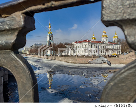 St. Nicholas Naval Cathedral belltower through the forged lattice in a clear sunny day of spring, an ice drift on Kryukov and Griboyedov Canal, a view of seven bridges from the embankment St. Nicholas Naval Cathedral belltower through the forged lattice in a clear sunny day of spring, an ice drift on Kryukov and Griboyedov Canal, a view of seven bridges from the embankment 76161306
