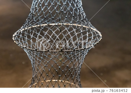 fish trap hanging vertically close-up on a blurred background fish trap hanging vertically close-up on a blurred background 76163452