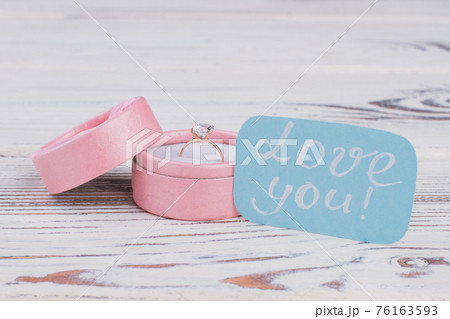 Wedding ring in present box on wooden background. 76163593
