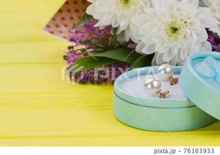 Box with jewelry and flowers on color background. 76163933