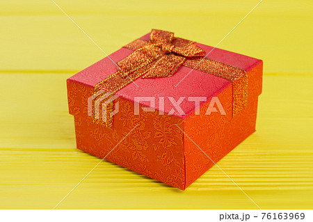 Red gift box on yellow wooden background. Red gift box on yellow wooden background. 76163969