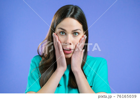Portrait of unpleasantly surprised and shocked girl on violet studio background. Woman receiving bad 76165039