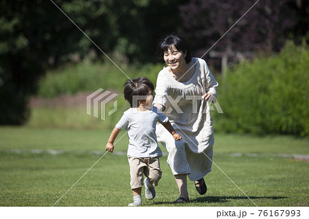 夏の芝生の上で鬼ごっこする親子 夏の芝生の上で鬼ごっこする親子 76167993