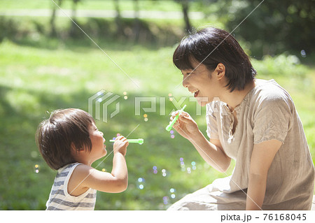 夏の庭でシャボン玉で遊ぶ親子 76168045