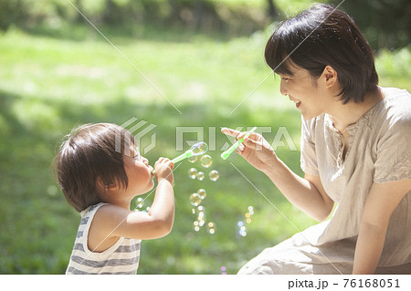夏の庭でシャボン玉で遊ぶ親子 76168051