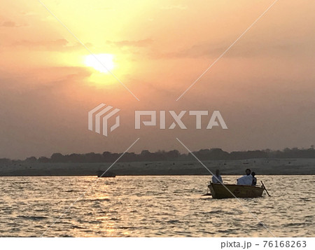 船に乗る人と沈む夕日 76168263