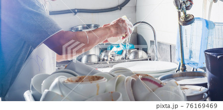 Man washing dish in sink 76169469