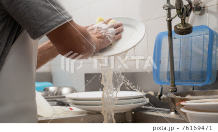 Man washing dish in sink Man washing dish in sink 76169471