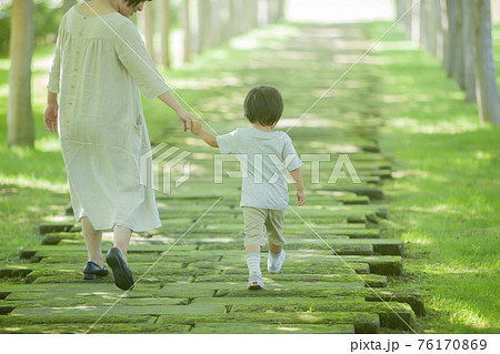 緑のトンネルを歩いていく親子 76170869