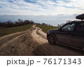 A gravel road leading toward horizon. Spectacular view on the sea and blue sky in the evening. Offroad 4x4 car 76171343