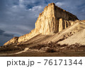 Beautiful white mountain peak lit by sun. White clouds and blue sky on background. Epic rock formation 76171344