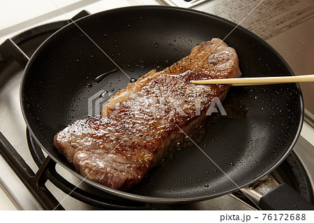 フライパンでこんがり焼かれるステーキ 76172688