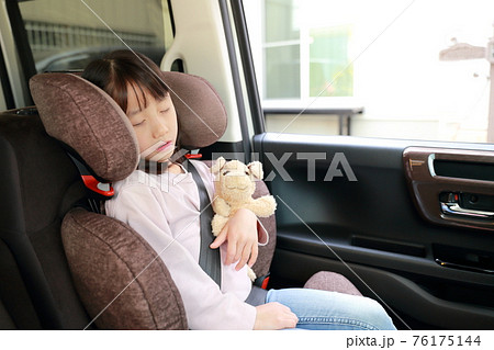 助手席に取り付けたジュニアシートに座って眠る女の子 76175144