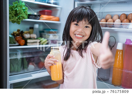 asian girl open fridge door drinking a bottle of juice asian girl open fridge door drinking a bottle of juice 76175809