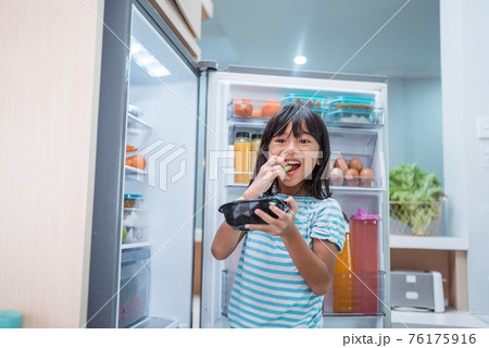 asian girl open fridge door drinking a bottle of juice asian girl open fridge door drinking a bottle of juice 76175916