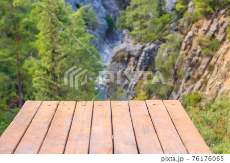 Empty wooden table on a green mountains landscape background Empty wooden table on a green mountains landscape background 76176065