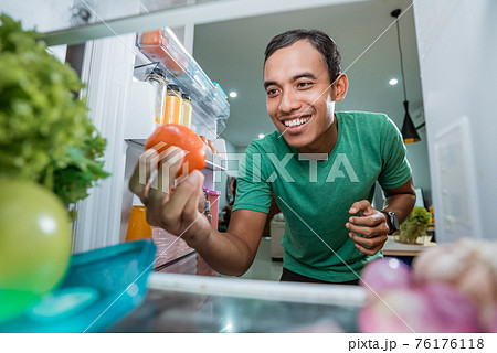 asian man taking ingredient out from the fridge to cook asian man taking ingredient out from the fridge to cook 76176118