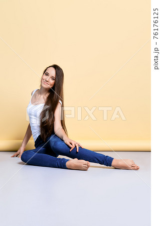 Barefoot girl in t-shirt and jeans sitting on the flook in studio Barefoot girl in t-shirt and jeans sitting on the flook in studio 76176125