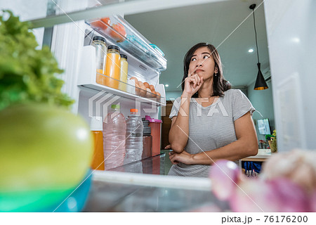 asian woman thinking while open the refrigerator door before cooking asian woman thinking while open the refrigerator door before cooking 76176200