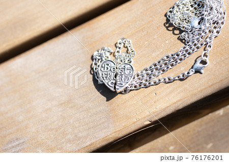 Set of best friends heart made up of two parts necklace shoot outside in a summer day closeup. Selective Focus 76176201