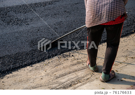 Construction worker using tool spread the hot-mix asphalt road accurately level covering on highway Construction worker using tool spread the hot-mix asphalt road accurately level covering on highway 76176633