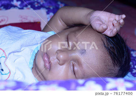 Close up face of a cute sleeping newborn baby. Closeup portrait of a Sweet just born infant boy captured in sleepy mood drowsy eyes. Hand on Head. Front view. Child care kid background image. Close up face of a cute sleeping newborn baby. Closeup portrait of a Sweet just born infant boy captured in sleepy mood drowsy eyes. Hand on Head. Front view. Child care kid background image. 76177400