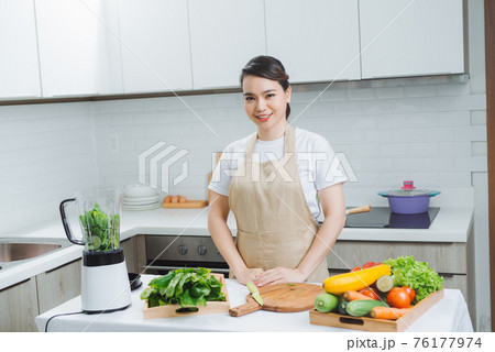 Woman cooking healthy detox smoothie with fresh fruits and green spinach, salad leaves. Lifestyle detox concept Woman cooking healthy detox smoothie with fresh fruits and green spinach, salad leaves. Lifestyle detox concept 76177974