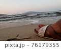 夕暮れ時の砂浜でビーチサンダルを履き休憩 76179355