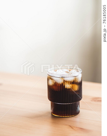 Cola glass with ice cubes on wood table Cola glass with ice cubes on wood table 76185005