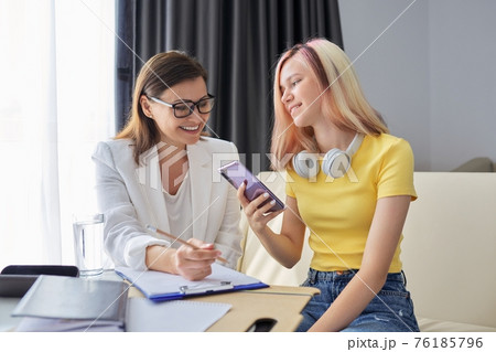 Professional counselor looks at smartphone screen with student girl Professional counselor looks at smartphone screen with student girl 76185796