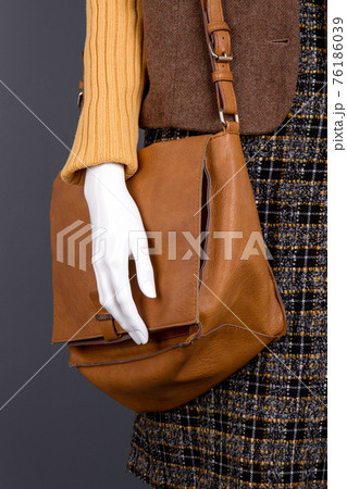 Brown leather handbag and mannequin hand. 76186039