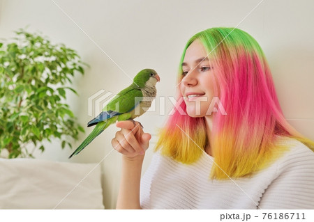 Trendy teen girl with green parrot on his hand Trendy teen girl with green parrot on his hand 76186711