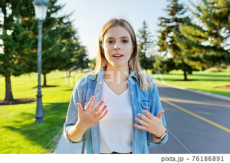 Gesturing young beautiful woman talking at camera, teenager student giving interview Gesturing young beautiful woman talking at camera, teenager student giving interview 76186891