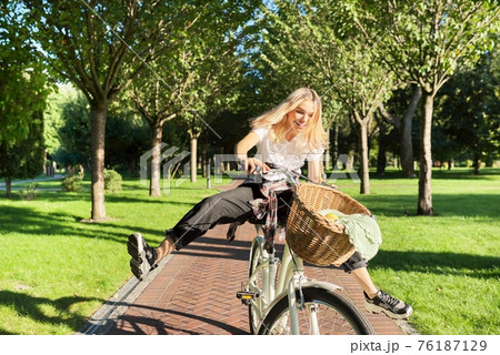 Happy young woman riding bike on road in park, beautiful hipter teenager having fun and laughing Happy young woman riding bike on road in park, beautiful hipter teenager having fun and laughing 76187129