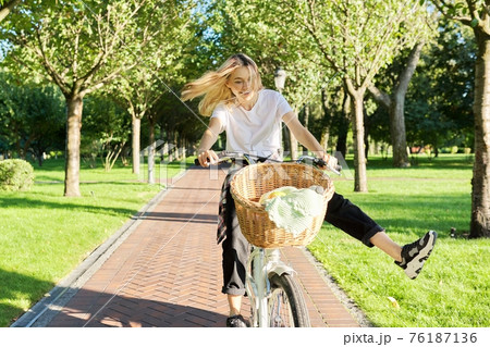 Happy young woman riding bike on road in park, beautiful hipter teenager having fun and laughing 76187136