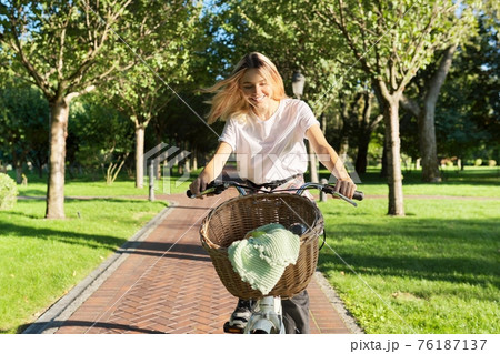 Young beautiful woman on vintage bike with basket rides on nature 76187137