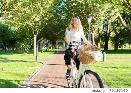 Young beautiful woman on vintage bike with basket rides on nature Young beautiful woman on vintage bike with basket rides on nature 76187140