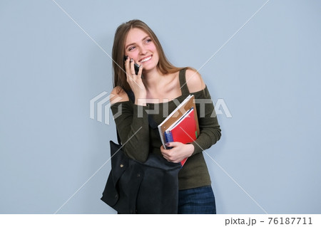Portrait of female university student with books backpack talking on mobile phone Portrait of female university student with books backpack talking on mobile phone 76187711