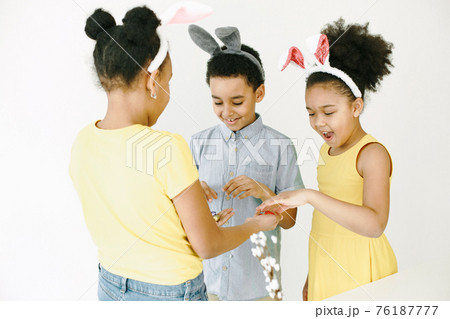 Children in yellow clothes paint Easter eggs Children in yellow clothes paint Easter eggs 76187777