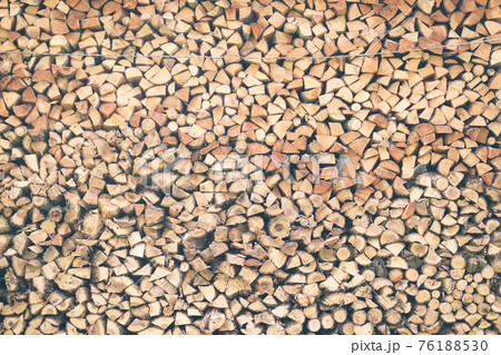 Firewood or fuelwood stacked by a wall. Wooden pile prepared for winter. Fuel for countryside fireplace. Forest timber energy concept, Texture woodpile. Kindling construction 76188530