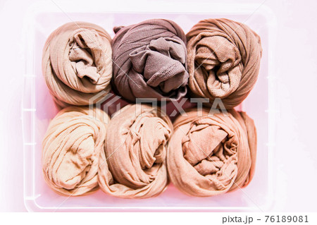 Colorful clothes vertical storage in home wardrobe. Tights in a plastic box on soft pink background 76189081