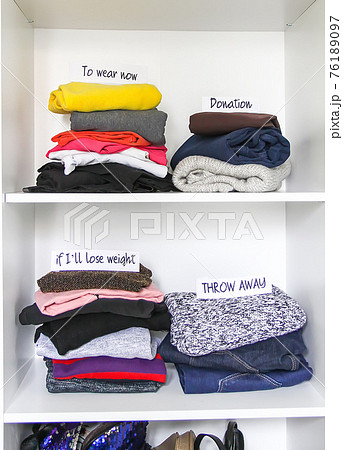 Different clothes in home wardrobe with paper notes. Small space organization. Vertical storage 76189097