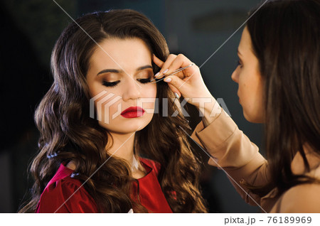 Close up of professional stylist lengthening lashes for female client in a beauty salon. Close up of professional stylist lengthening lashes for female client in a beauty salon. 76189969