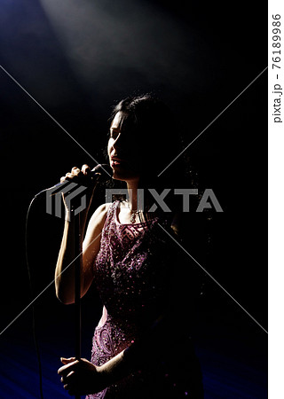 Portrait of beautiful singing woman on dark background. 76189986