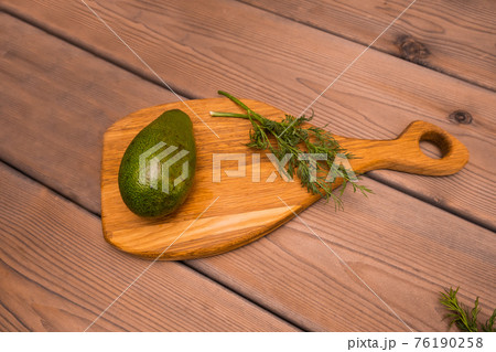 Fresh whole vegetable avocado and green dill lie on a chopping board. Veganism. Vegetarian food Fresh whole vegetable avocado and green dill lie on a chopping board. Veganism. Vegetarian food 76190258