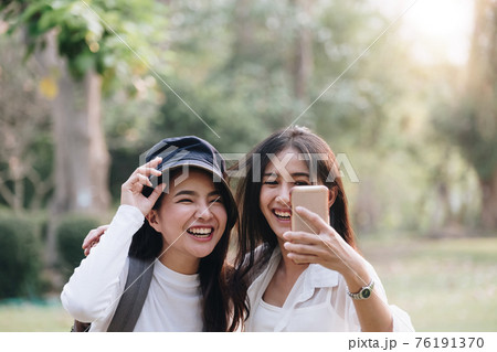 Happy two young attractive asian girls take a selfie at the park Happy two young attractive asian girls take a selfie at the park 76191370