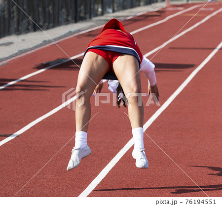 Cheerleader perfomrning flips on a red track 76194551