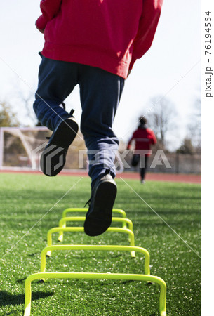 Athlete in air jumping over yellow mini hurdles 76194554