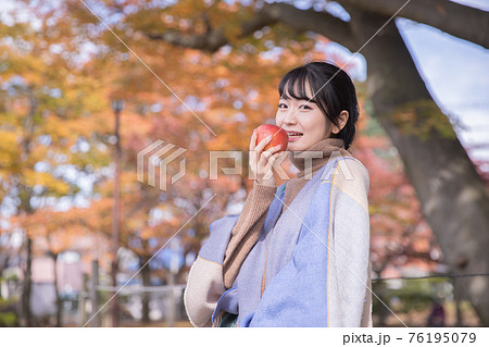秋の公園でりんごを食べる女性 秋の公園でりんごを食べる女性 76195079